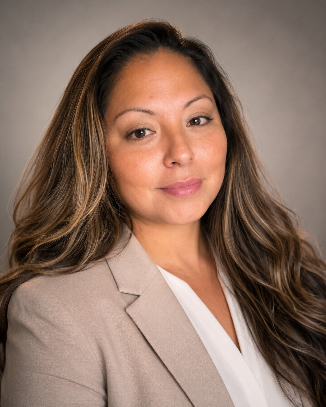 Professional headshot of Erika A. Vélez wearing a taupe blazer